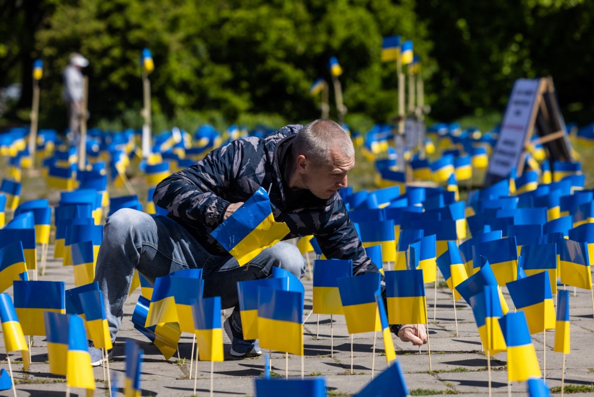 A man sticks a flag beside other Ukrainian flags, during a protest organized by activists of the Ukrainian diaspora in Warsaw, on May 9, 2023. (Photo by Wojtek Radwanski / AFP)