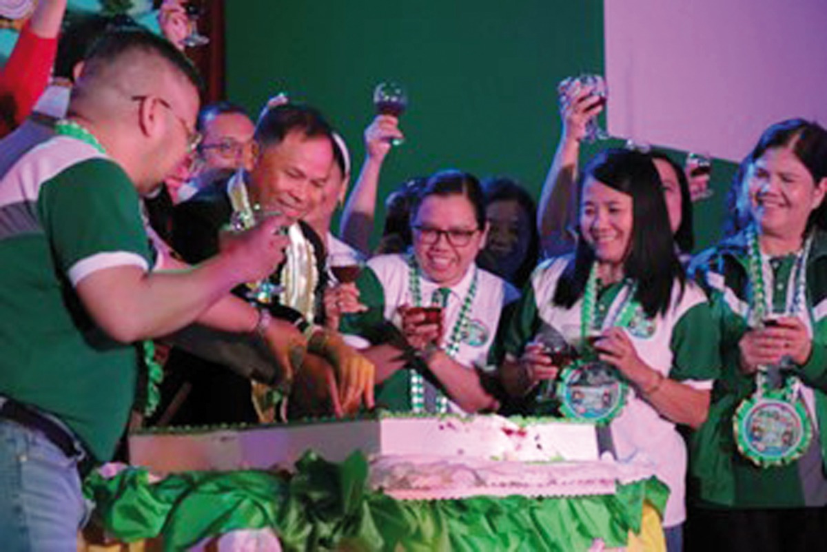 School Principal Dr. Alexander S Acosta and others cutting a cake to mark the anniversary. 