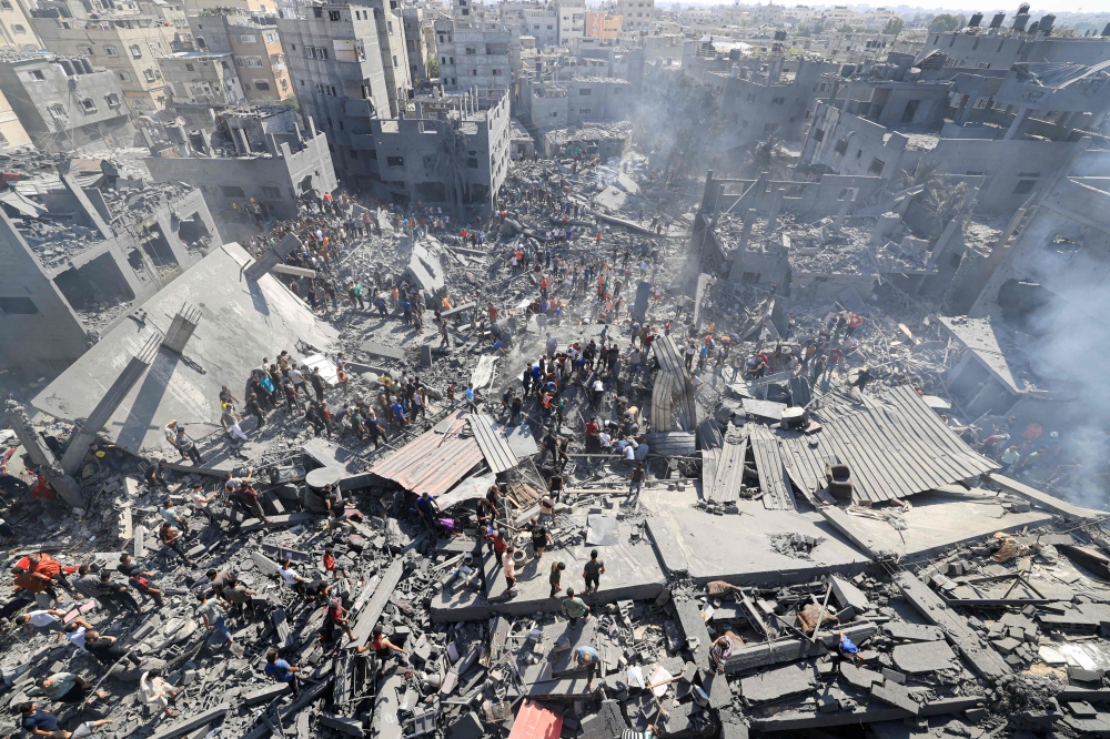 People search for survivors and the bodies of victims through the rubble of buildings destroyed during Israeli bombardment, in Khan Yunis in the southern Gaza Strip on October 26, 2023, amid the ongoing battles between Israel and the Palestinian group Hamas. Photo by Mahmud HAMS / AFP
