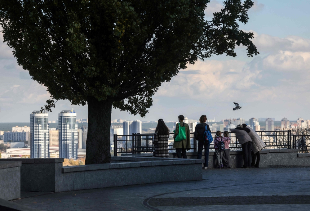 People look at the skyline of the Kyiv from a park, on October 27, 2023. (Photo by Anatolii Stepanov / AFP)
