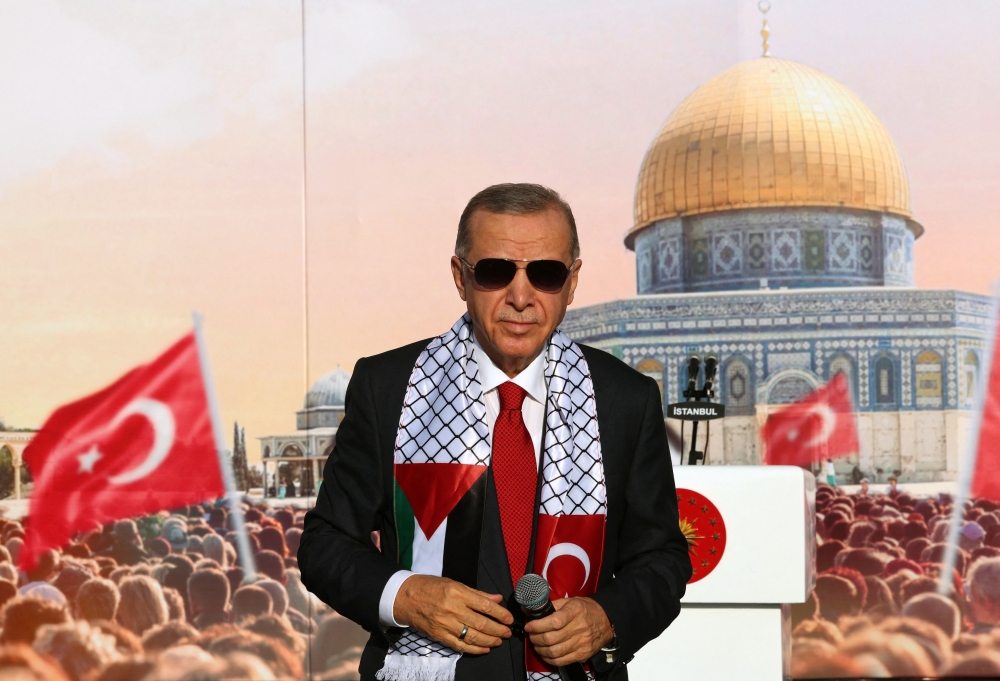 Turkish President Tayyip Erdogan, wearing a scarf with the Palestinian and Turkish flags, stands on the stage during a rally organised by the AKP party in solidarity with the Palestinians in Gaza, in Istanbul on October 28, 2023. (Photo by Handout / Turkish Presidency Press Office / AFP) 