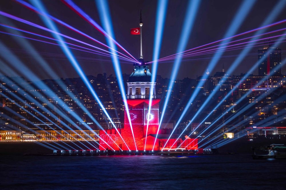 A photograph taken in Istanbul on October 29, 2023, shows the Turkish flag waving on the illuminated Maiden's Tower during celebrations to mark the 100th anniversary of the Turkish Republic. (Photo by Yasin Akgul / AFP)