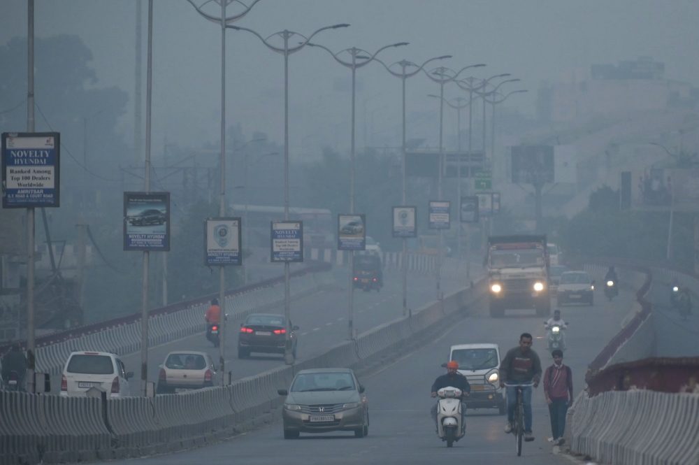 Commuters make their way along a road amid heavy smog conditions in of Amritsar on November 3, 2023. Photo by Narinder NANU / AFP
