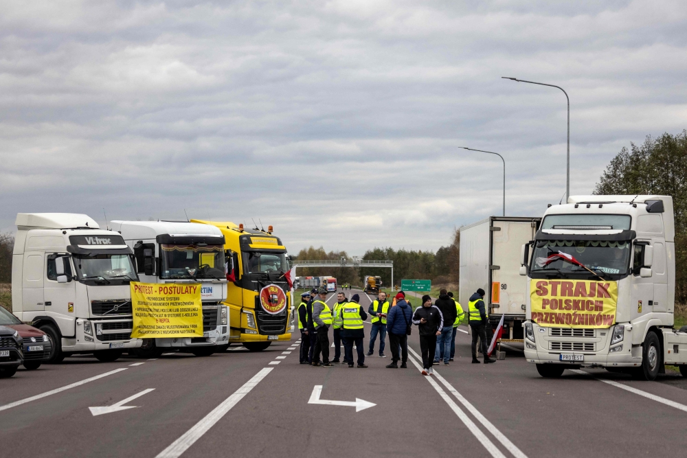 Transport company owners stand together as they with their vehicles block access to the Polish-Ukrainian border crossing in Dorohusk, Poland on November 6, 2023 to protest against 'unfair' competition. (Photo by Wojtek Radwanski / AFP)
