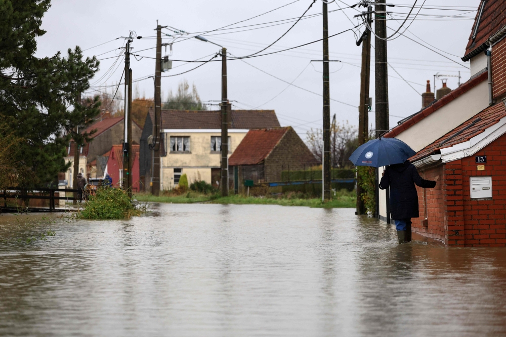A woman walks in a flooded street in Le Doulac near Saint-Omer, northern France on November 14, 2023, as the Pas-de-Calais region was hit by torrential rains with a historic rise in water levels on November 7, 2023. Photo by Aurelien Morissard / POOL / AFP