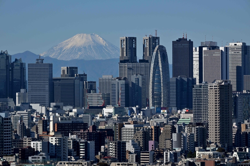 This picture taken on November 14, 2023 shows Japan's highest mountain, Mt. Fuji in the background between skyscrapers in Tokyo's Shinjuku area. (Photo by Kazuhiro NOGI / AFP)