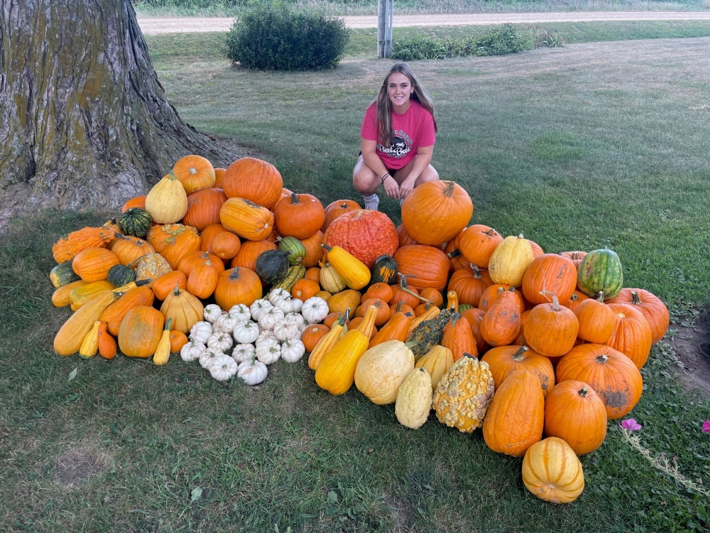 Lauren Schroeder with pumpkins, squash and gourds picked from her garden in Dixon, Iowa. Credit: Katie Schroeder