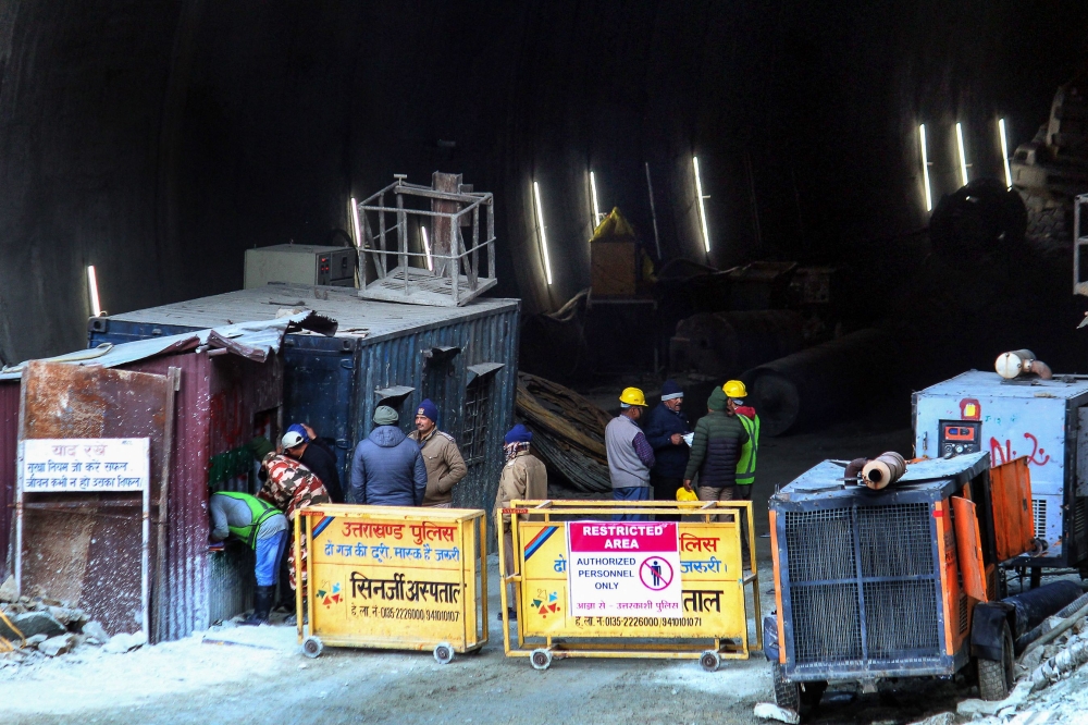 Police and officials stand at the entrance of the under construction road tunnel that collapsed in Uttarkashi district on November 17, 2023. (Photo by AFP)