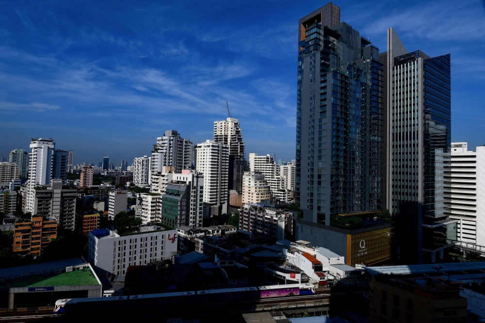 A general view shows a BTS commuter train as it passes with the backdrop of the Bangkok skyline on June 2, 2023. Photo by Manan VATSYAYANA / AFP

