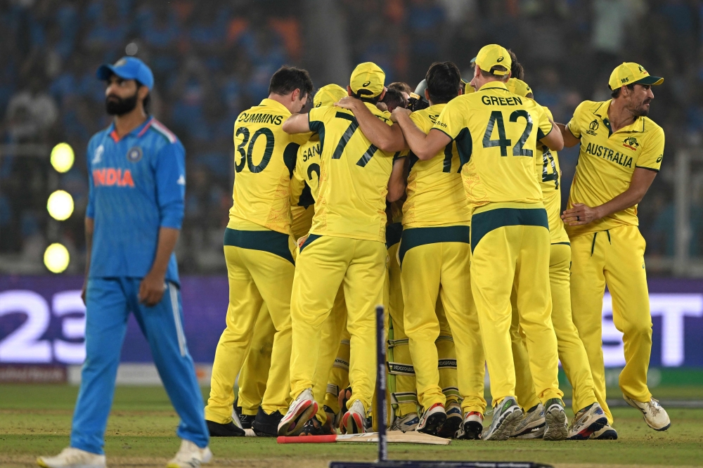 India's Ravindra Jadeja (L) walks past Australia's players celebrating their win in the 2023 ICC Men's Cricket World Cup one-day international (ODI) final match between India and Australia at the Narendra Modi Stadium in Ahmedabad on November 19, 2023. (Photo by Punit PARANJPE / AFP)