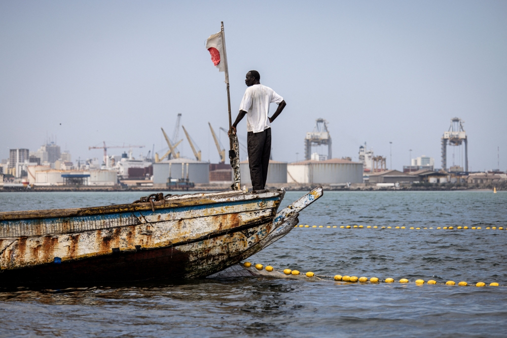 A fisherman looks on from his boat in the polluted Hann Bay in Dakar, on September 27, 2023. (Photo by John Wessels / AFP)