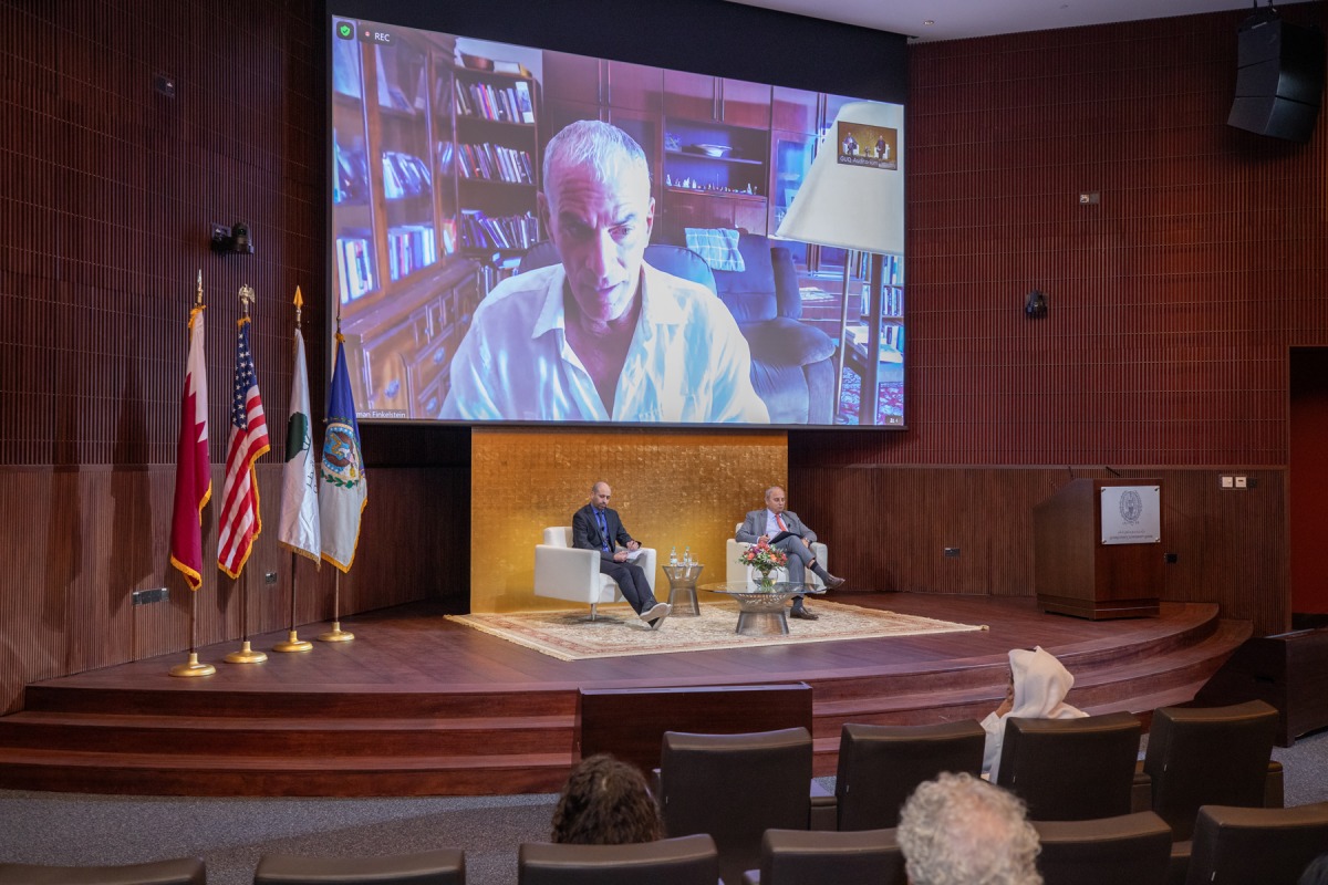 Dean of GU-Q Dr. Safwan Masri (right) and Associate Professor of History at GU-Q Dr. Abdullah Al Arian (left) on the stage while Dr. Norman Finkelstein is speaking virtually at the public event in Doha.