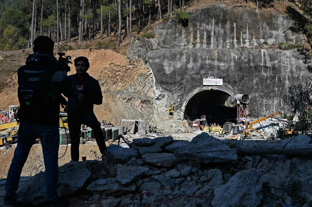 Media personnel stand near an entrance of the Silkyara under construction road tunnel in the Uttarkashi district of India's Uttarakhand state on November 23, 2023. (Photo by Arun Sankar / AFP)