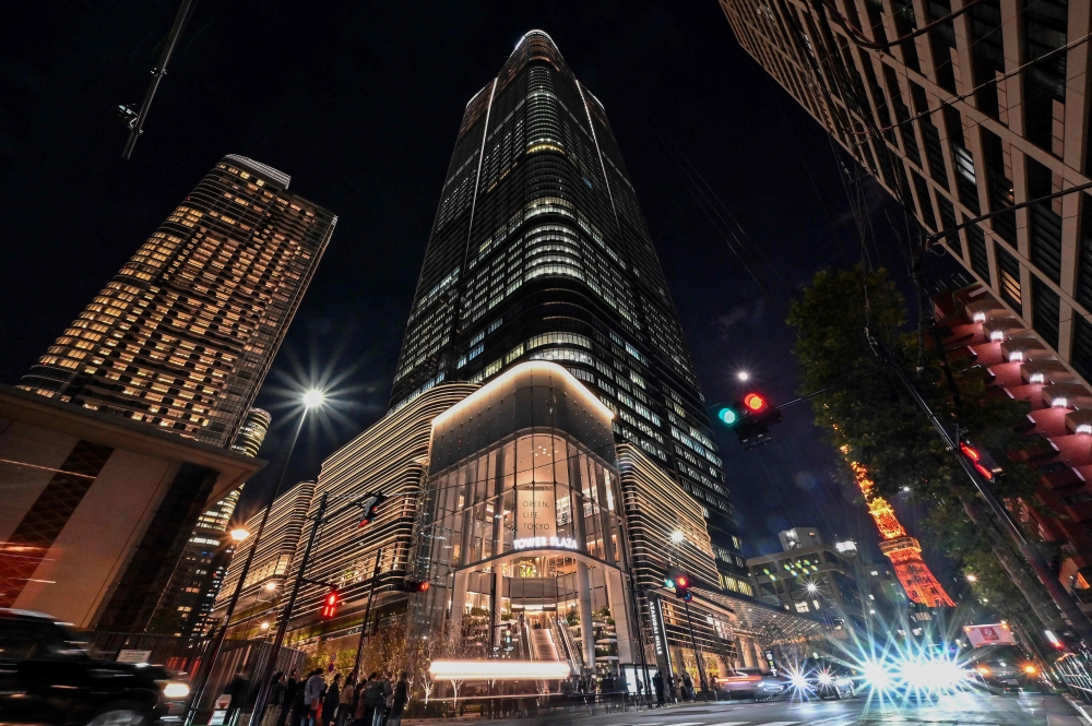 This general view shows a night view of Tokyo's newest skyscraper, the Azabudai Hills Mori JP Tower complex, after its official opening earlier in the day as Tokyo Tower (back R) looms nearby in central Tokyo on November 24, 2023. Photo by Richard A. Brooks / AFP