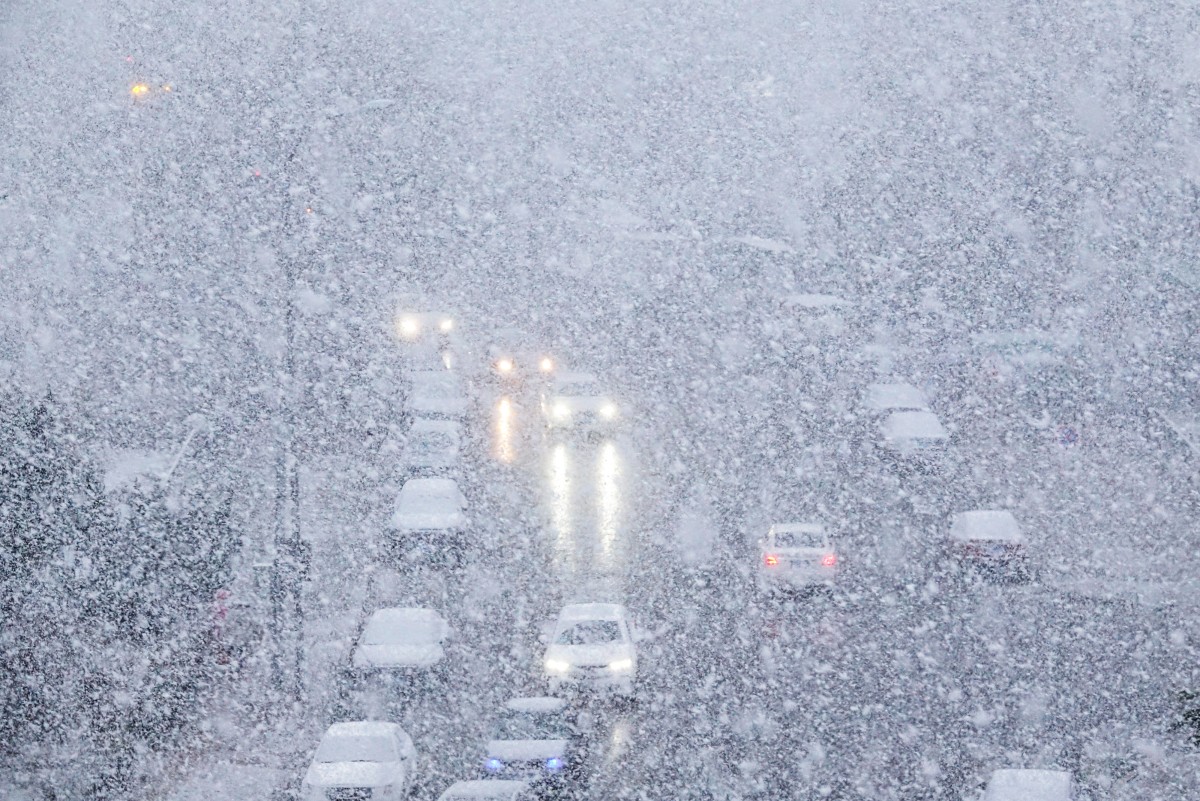 Cars make their way during snowfall in Dalian, in China's northeastern Liaoning province on November 23, 2023. Photo by AFP