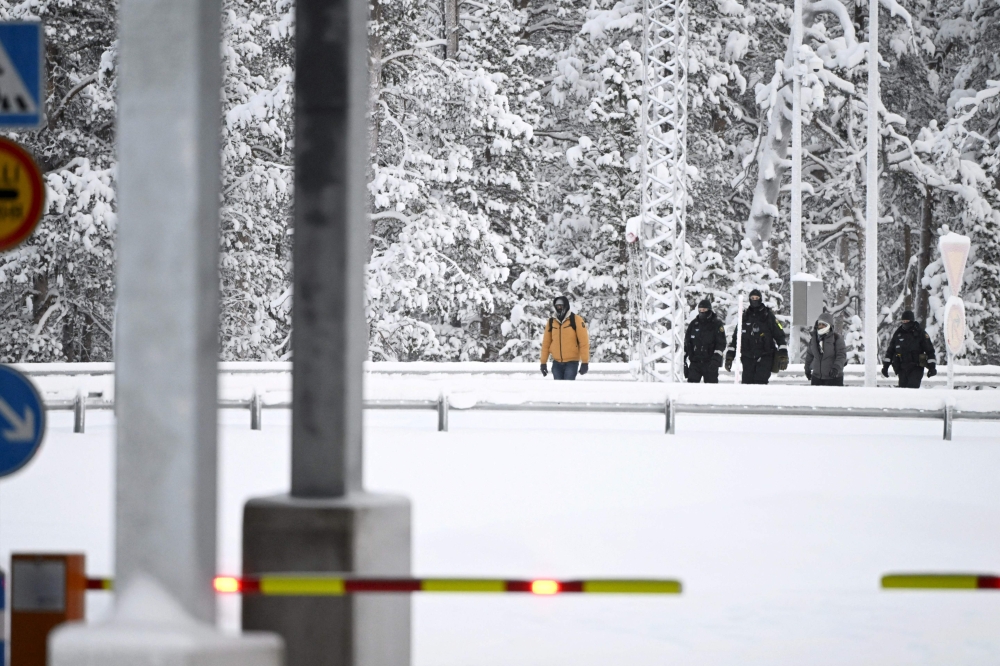 Finnish Border Guards escort two migrants at the Raja-Jooseppi international border crossing station in Inari, northern Finland, on November 27, 2023. (Photo by Emmi Korhonen / Lehtikuva / AFP) / Finland OUT
