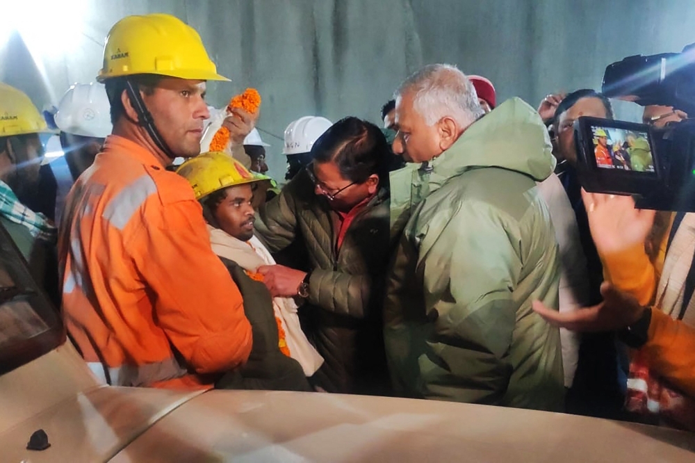 This handout picture released by the Uttarakhand's Department of Information and Public Relation (DIPR) and taken on November 28, 2023 shows a contruction worker (front 2L) interacting with Chief minister of Uttarakhand Pushkar Singh Dhami (C) following his rescue from inside the under construction Silkyara tunnel during a rescue operation for trapped workers after a section of the tunnel collapsed in the Uttarkashi district of India's Uttarakhand state. (Photo by Department of Information and Public Relation (DIPR) Uttarakhand / AFP) 