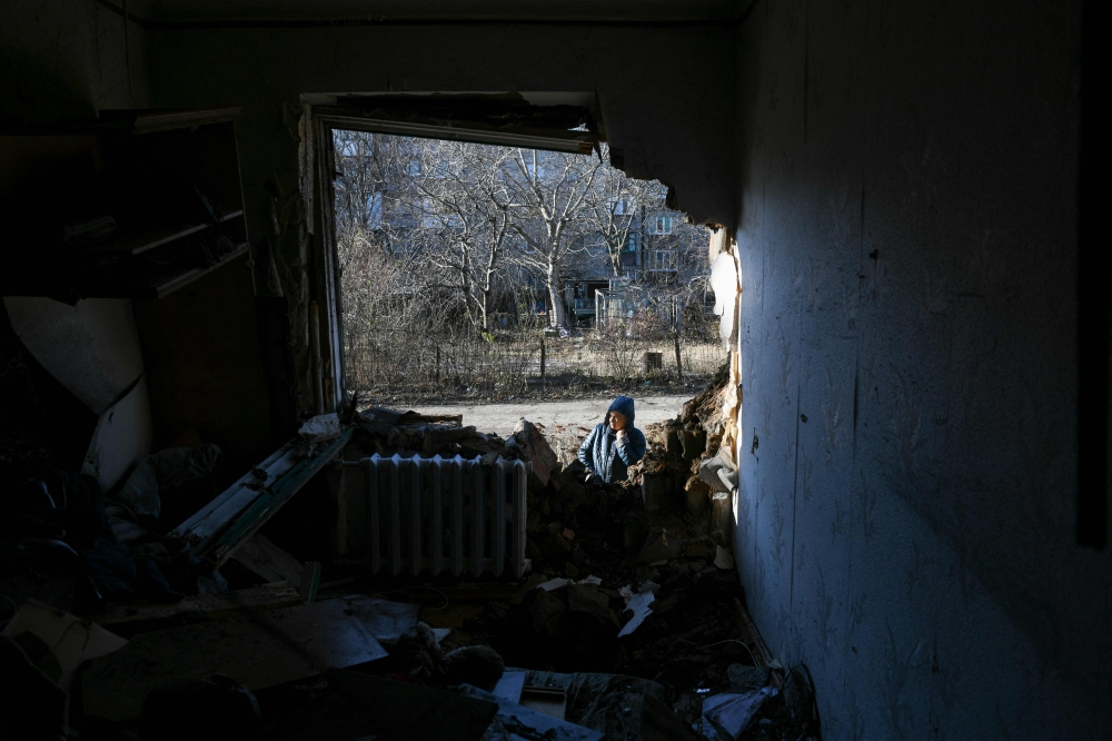 A local resident stands outside an apartment building damaged by recent shelling in Donetsk, on November 28, 2023. (Photo by STRINGER / AFP)