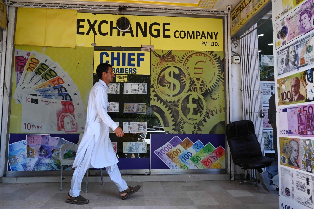 File: A man walks past foreign currency exchange market in Islamabad on July 11, 2023. (Photo by Aamir Qureshi / AFP)