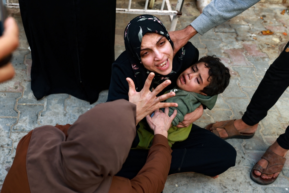 A woman holding a child mourns her baby girl killed in an Israeli strike in Rafah in the southern Gaza Strip, as she waits to receive the body for burial in the courtyard of the al-Najjar hospital on December 1, 2023. (Photo by Mohammed Abed / AFP)