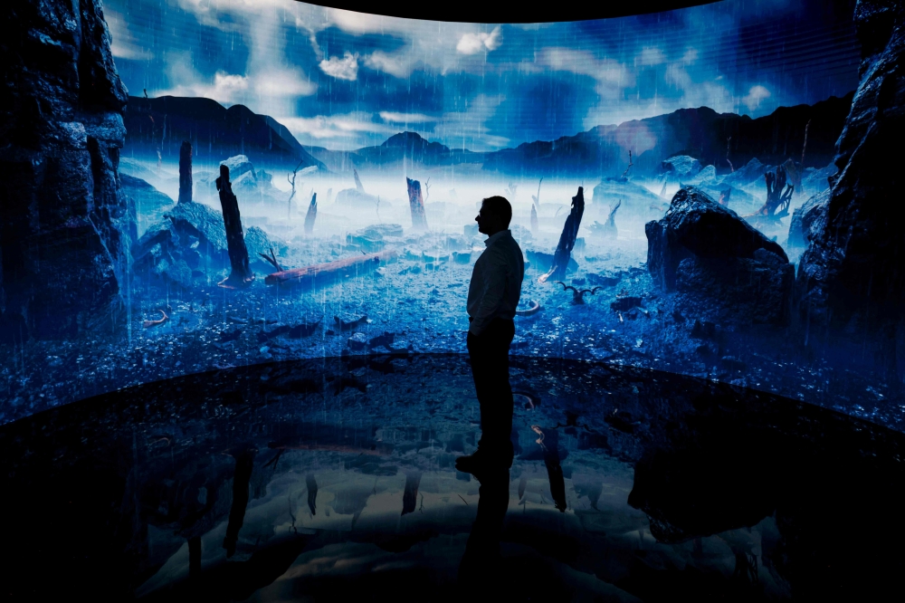 A man looks at a digital display at an exhibition by the Andrey Melnichenko Foundation during the COP28 United Nations climate summit in Dubai on December 1, 2023. (Photo by Ludovic Marin / AFP)
 