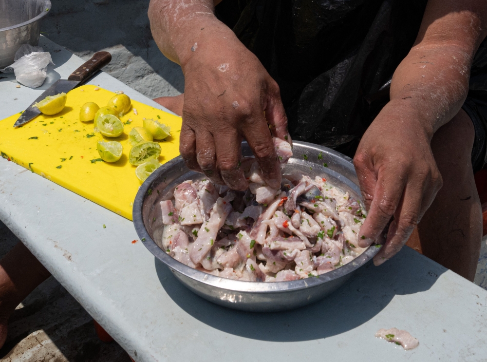 Peruvian artisan fisherman Cesar Melgarejo prepares a traditional ceviche for himself and colleagues with grey mullets (lisa in Spanish) caught in the early morning, while floating in the Lima Bay on December 1, 2023. (Photo by Cris Bouroncle / AFP)