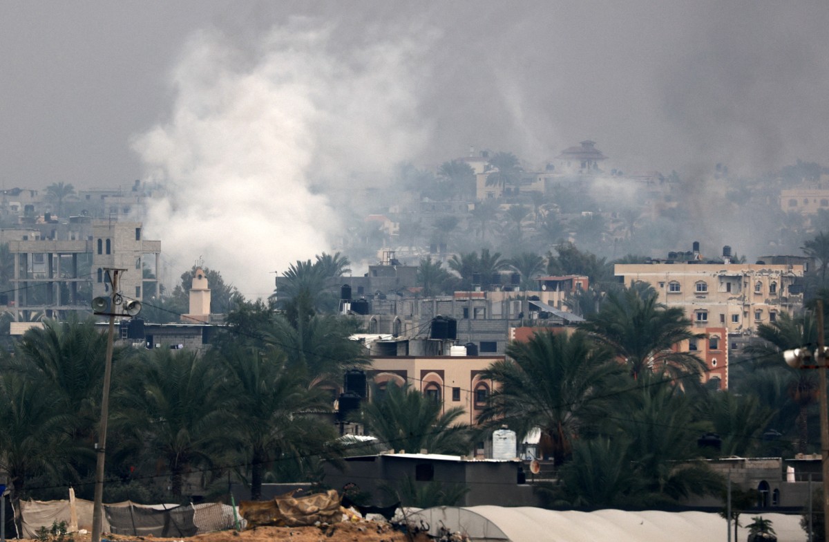 Smoke rises above buildings in Khan Yunis in the southern Gaza Strip on December 5, 2023. Photo by MAHMUD HAMS / AFP