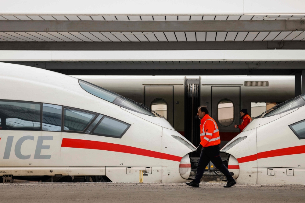 Employees walk past ICE highspeed trains that are standing still in the main train station of Munich, southern Germany, during a wage strike by German train drivers on December 8, 2023. Photo by Michaela Rehle / AFP