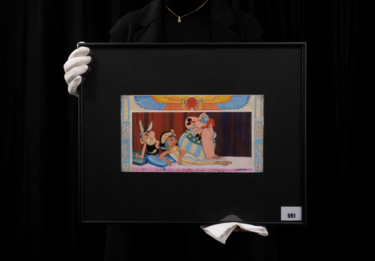 An employee holds a drawing by late French cartoonist Albert Uderzo, which appeared on the original cover of 