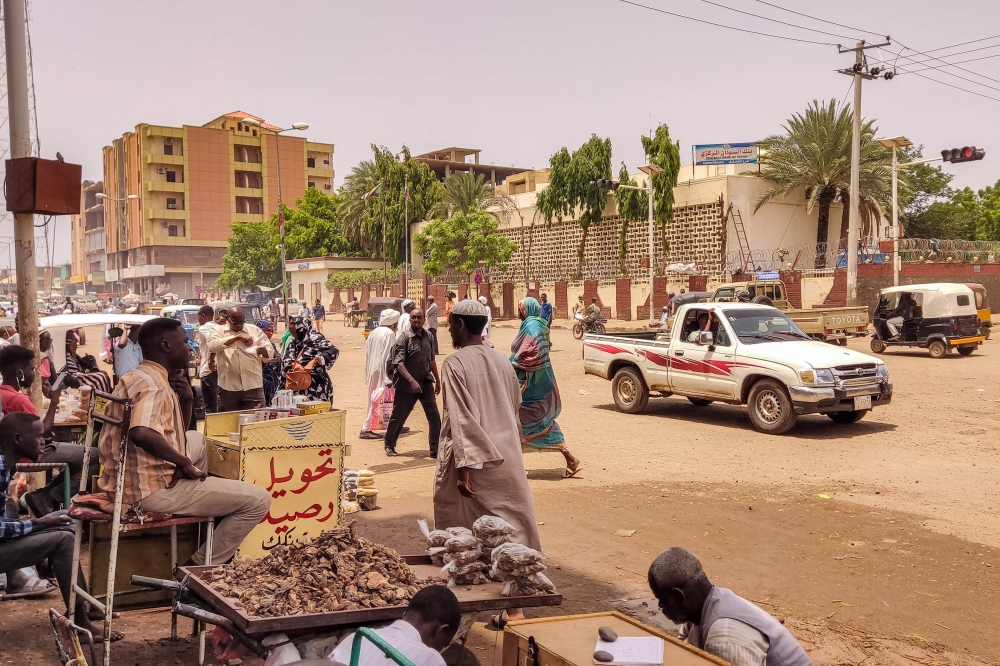 File: Pedestrians and vehicles move along a road outside a branch of the Central Bank of Sudan in the country's eastern city of Gedaref on July 9, 2023. (Photo by AFP)
