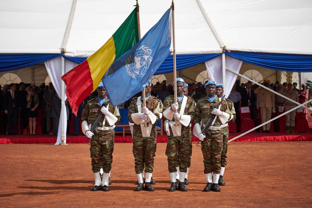 (FILES) Soldiers hold the UN and Malian flags during the ceremony of Peacekeepers' Day at the operating base of MINUSMA (The United Nations Multidimensional Integrated Stabilization Mission in Mali) in Bamako on May 29, 2018.(Photo by Michele CATTANI / AFP)
