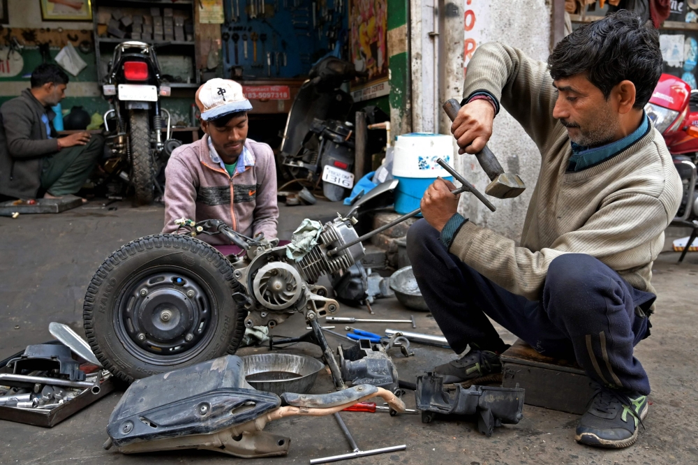Workers repair a scooter at their workshop in Amritsar on December 12, 2023. (Photo by Narinder NANU / AFP)