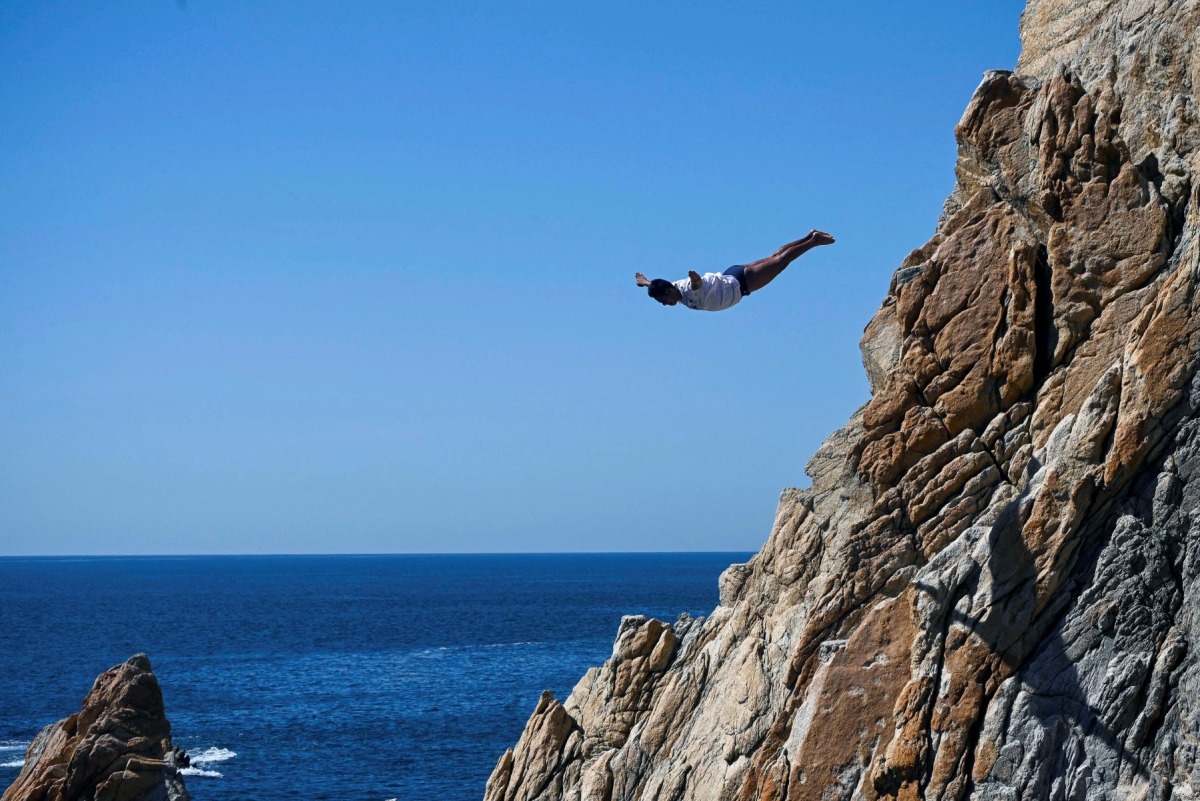 A cliff diver of La Quebrada performs after resuming activities following the passage of Hurricane Otis in Acapulco, Guerrero state, Mexico on December 8, 2023. Photo by Francisco Robles / AFP