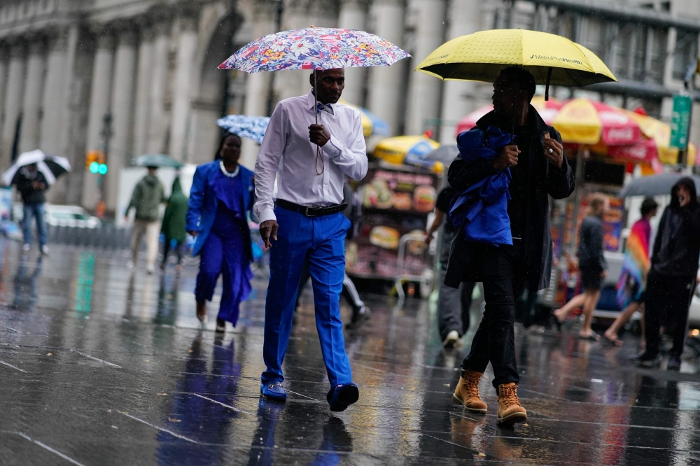 File photo: People walk under umbrellas during a coastal storm in Lower Manhattan on September 29, 2023 in New York City. (Photo by Eduardo Munoz Alvarez/Getty Images/AFP)