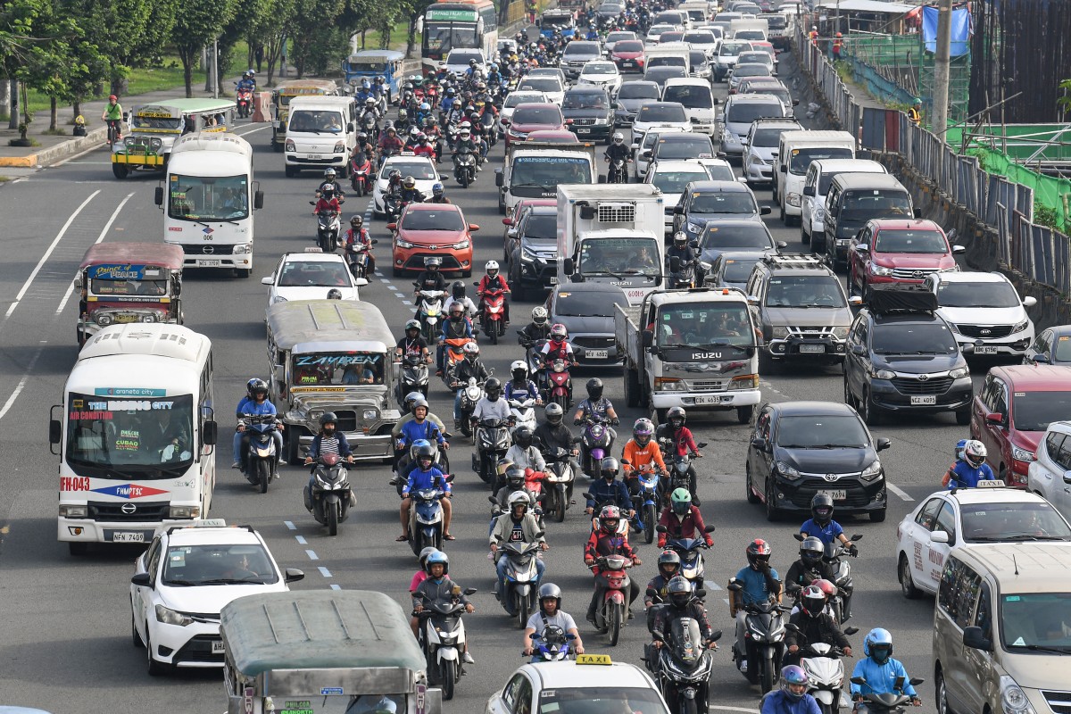 Motorists and vehicles travel along a road amid traffic jam in Manila on November 24, 2023. (Photo by Ted ALJIBE / AFP)

