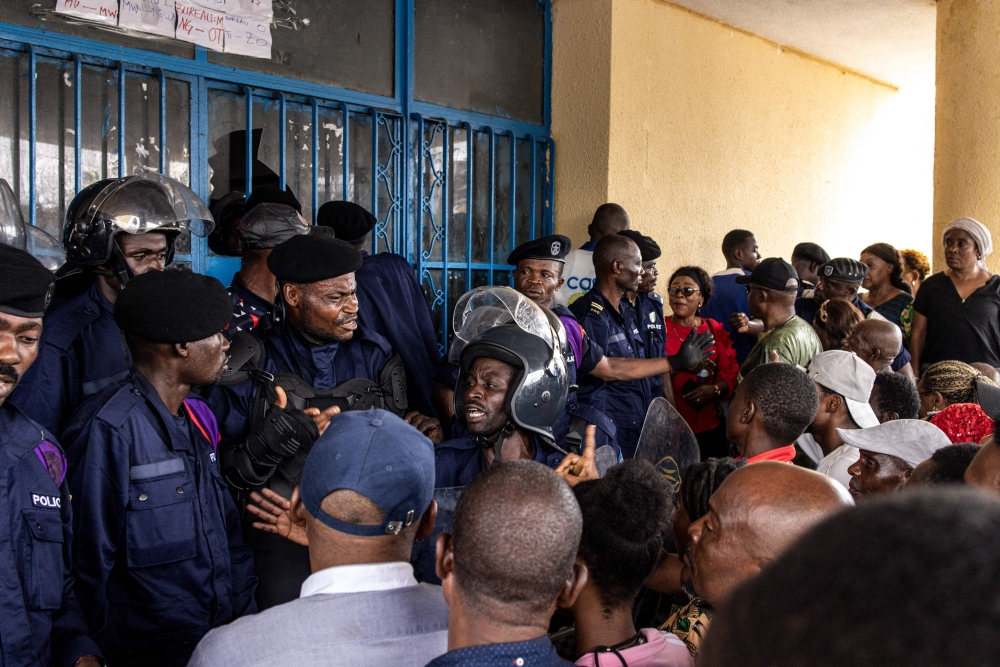 Congolese police officers block an entry after voters forced their way into a voting station in Kinshasa on December 20, 2023. (Photo by JOHN WESSELS / AFP)