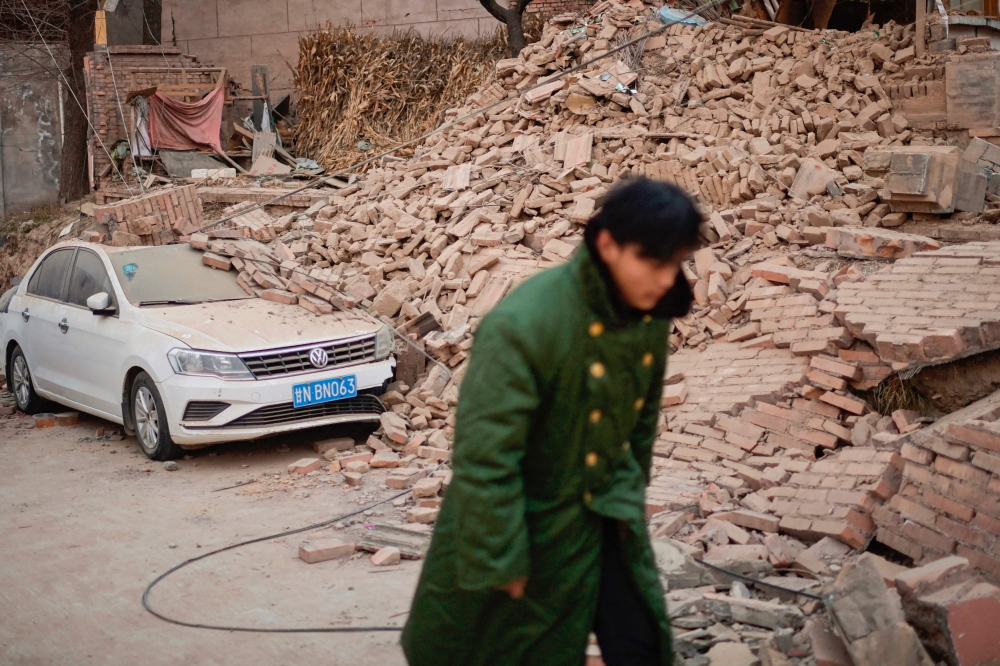 A man walks past a collapsed house in Dahejia in Jishishan County in northwest China's Gansu province on December 20, 2023. (Photo by Pedro Pardo / AFP)
