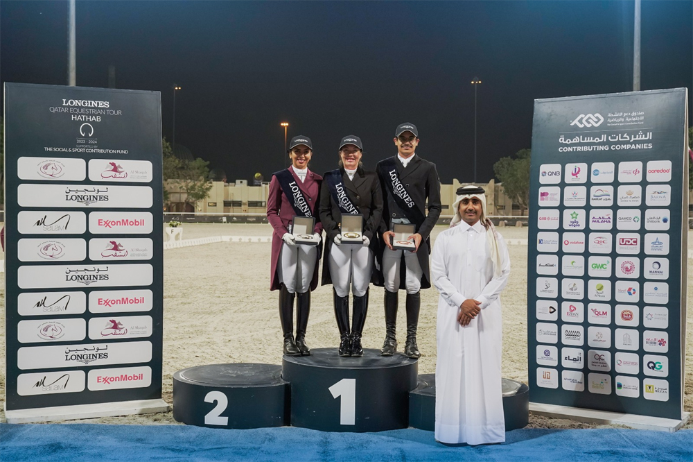 Michelle Grimes (centre), Maryam Ahmed Alsemaitt (left) and Saoud Ahmed Al Boinin pose on the podium with Hathab Deputy Director Faisal Al Kahla at QEF Outdoor Arena yesterday.   