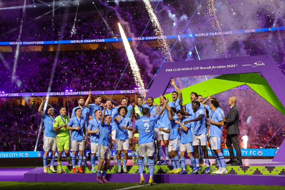 :Manchester City players celebrate with their winning trophy at the end of the FIFA Club World Cup 2023 football final match against Brazil's Fluminense at King Abdullah Sports City Stadium in Jeddah on December 22, 2023. (Photo by Giuseppe CACACE / AFP)
