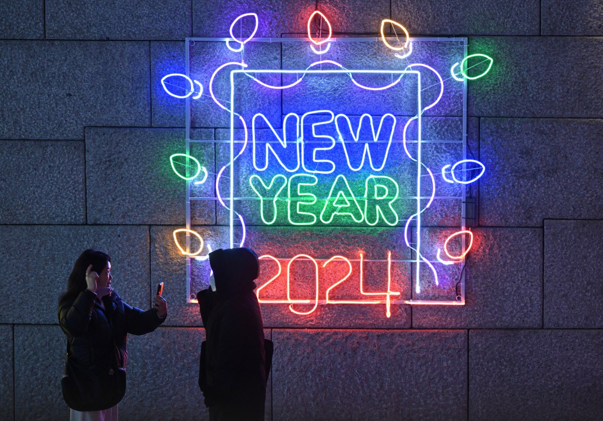 People take pictures in front of a light display reading 