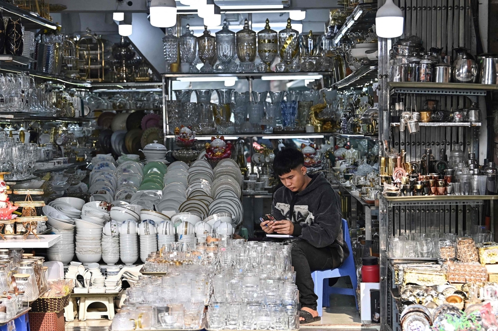 A man use his mobile phone at a household appliances shop in Hanoi on December 29, 2023. Photo by Nhac NGUYEN / AFP