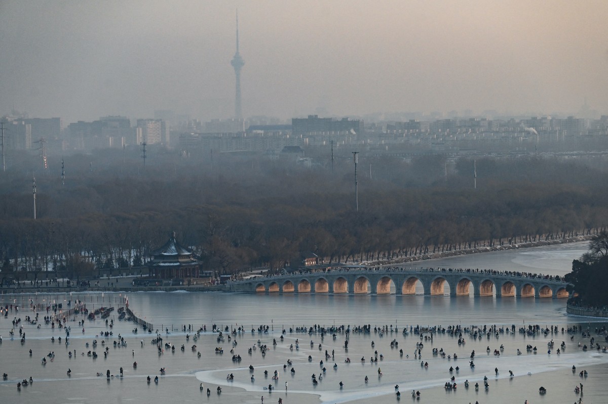 People ride sleds on a frozen lake at the Summer Palace during sunset in Beijing on December 28, 2023. (Photo by JADE GAO / AFP)

