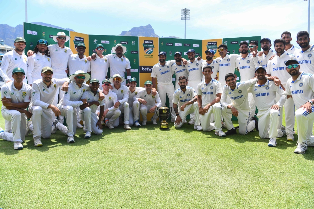 South Africa (L) and India (R) players pose with the trophy after drawing the series at Newlands stadium in Cape Town on January 4, 2024. (Photo by Rodger Bosch / AFP)
