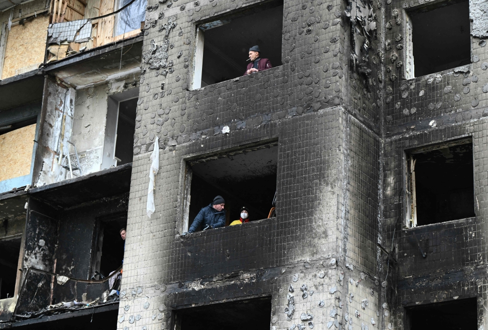 Local residents look from windows of a heavily damaged residential building, three days after a Russian missile attack in Kyiv, on January 5, 2024. (Photo by Genya Savilov / AFP)
 