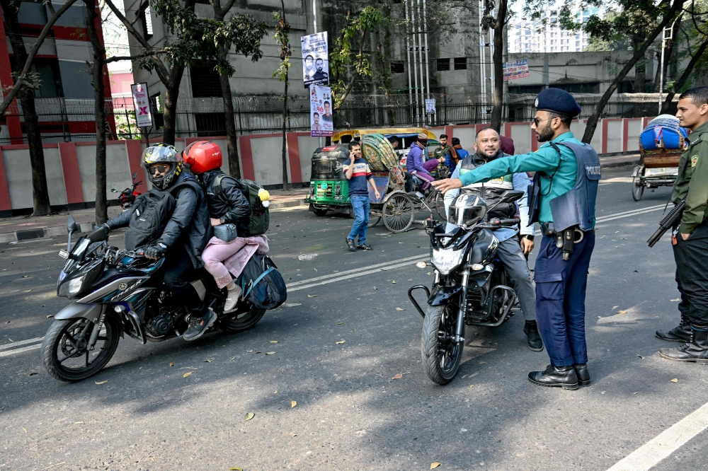 Police personnel inspect vehicles at a checkpoint near a polling station during Bangladesh's general elections in Dhaka on January 7, 2024. (Photo by Indranil Mukherjee / AFP)