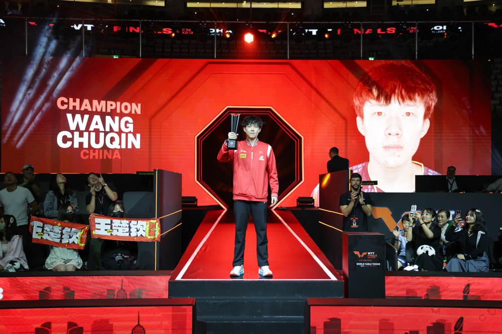 Men's singles champion Wang Chuqin celebrtaes with the trophy.