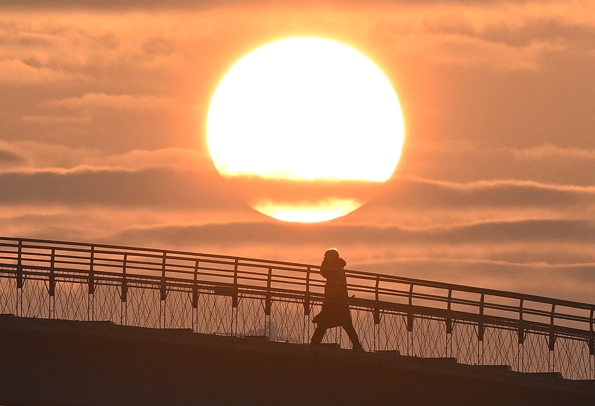 A person crosses a footbridge as the first sunrise of the new year is seen in Seoul on January 1, 2024. (Photo by Jung Yeon-je / AFP)