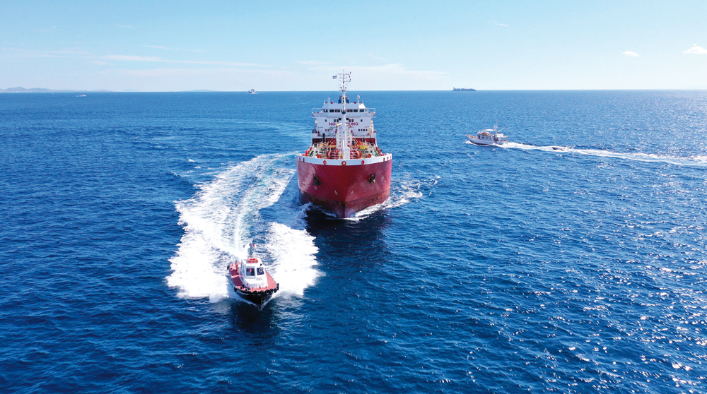 An aerial view of a pilot boat and large crude oil tanker cruising in the open ocean.