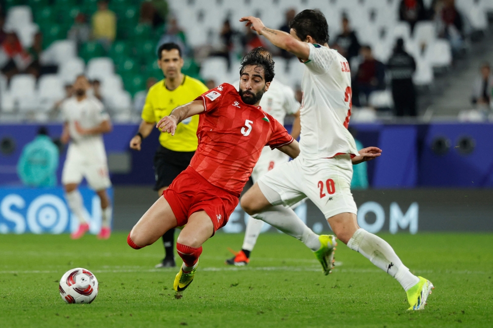 Palestine's defender #05 Mohammed Saleh and Iran's forward #20 Sardar Azmoun vie for the ball during the Qatar 2023 AFC Asian Cup Group C football match between Iran and Palestine at the Education City Stadium in Al-Rayyan, west of Doha on January 14, 2024. (Photo by KARIM JAAFAR / AFP)
