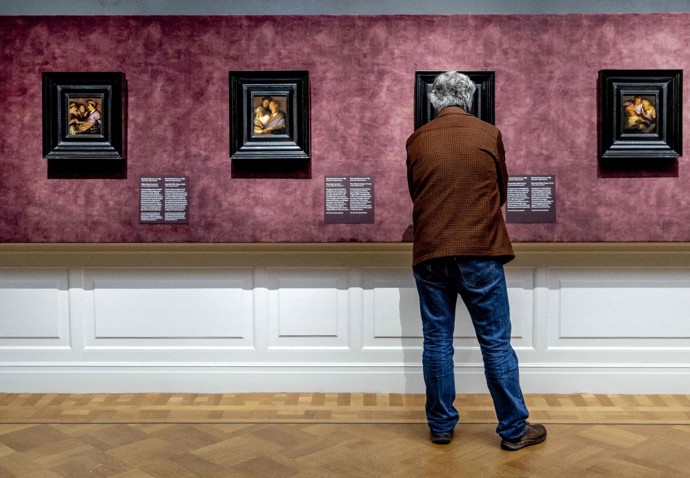 A person looks at painting during the preview of the exhibition 'Rembrandt's four senses - his first paintings' in the De Lakenhal museum in Leiden, on January 18, 2024. Photo by Remko de Waal / ANP / AFP